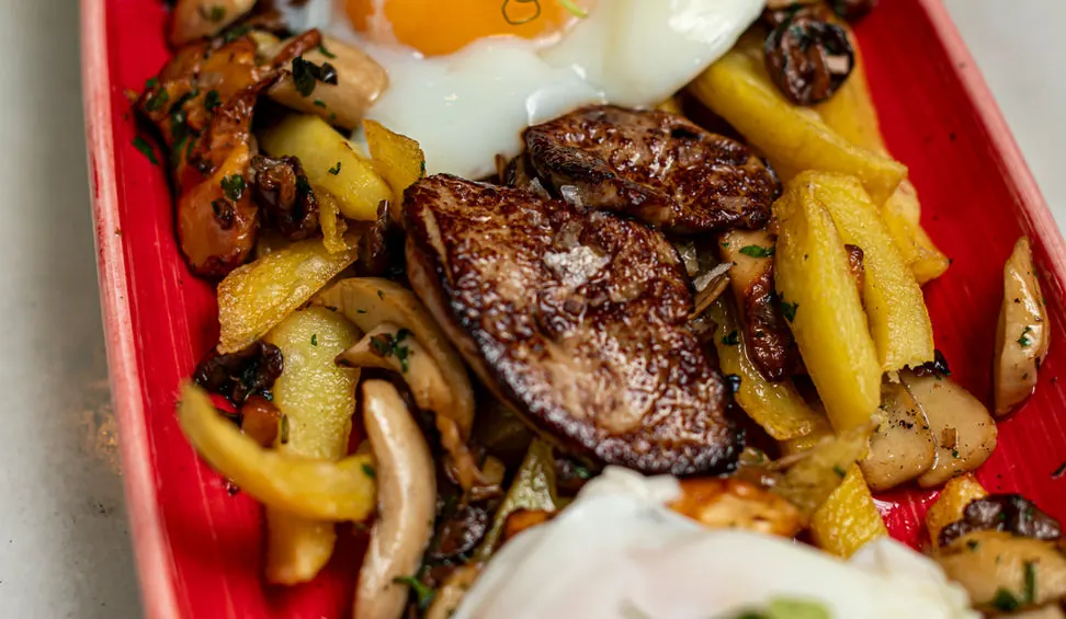 Fried eggs over chips with sautéed mushrooms