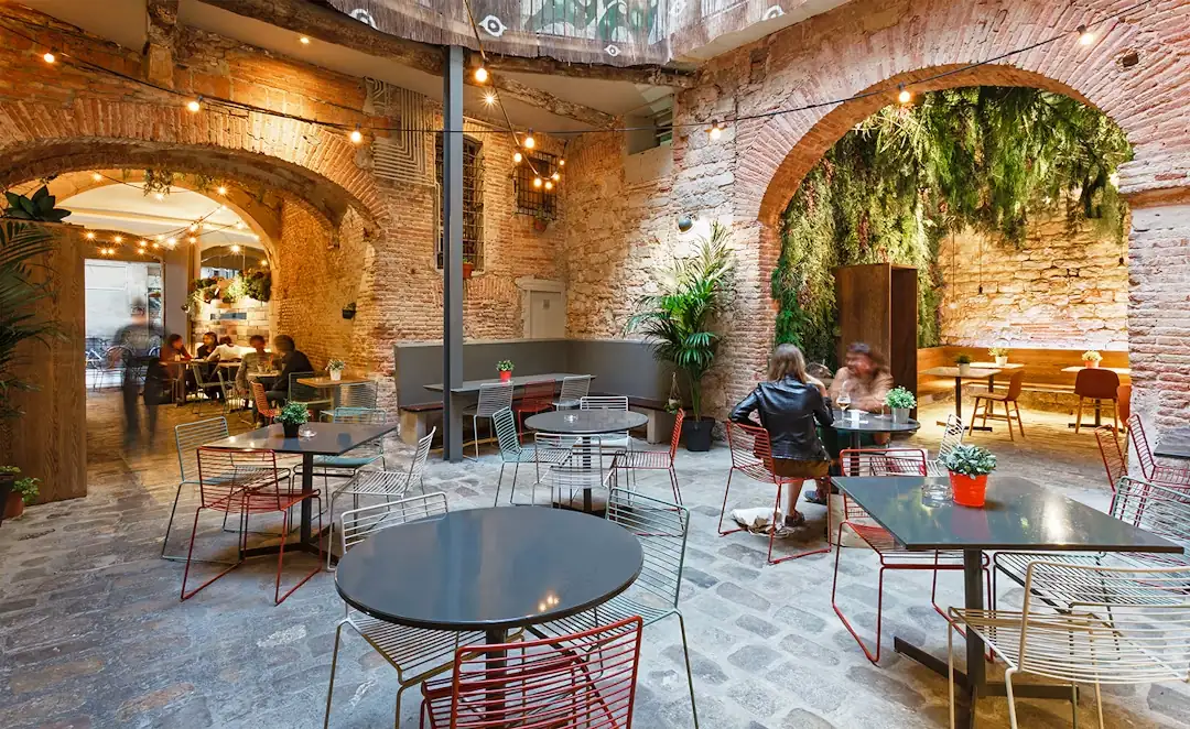 The indoor terrace at La Bona Sort, with tables and plants under the stone arches