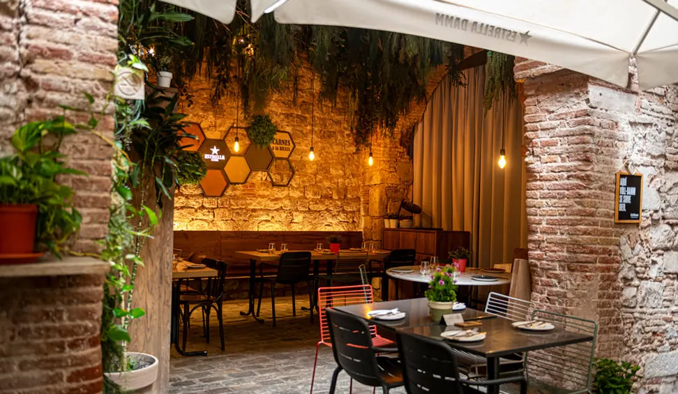 The dining area under a stone arch, with plants and warm light